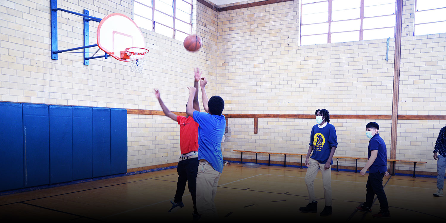 Students playing basketball in Riverside gym.
